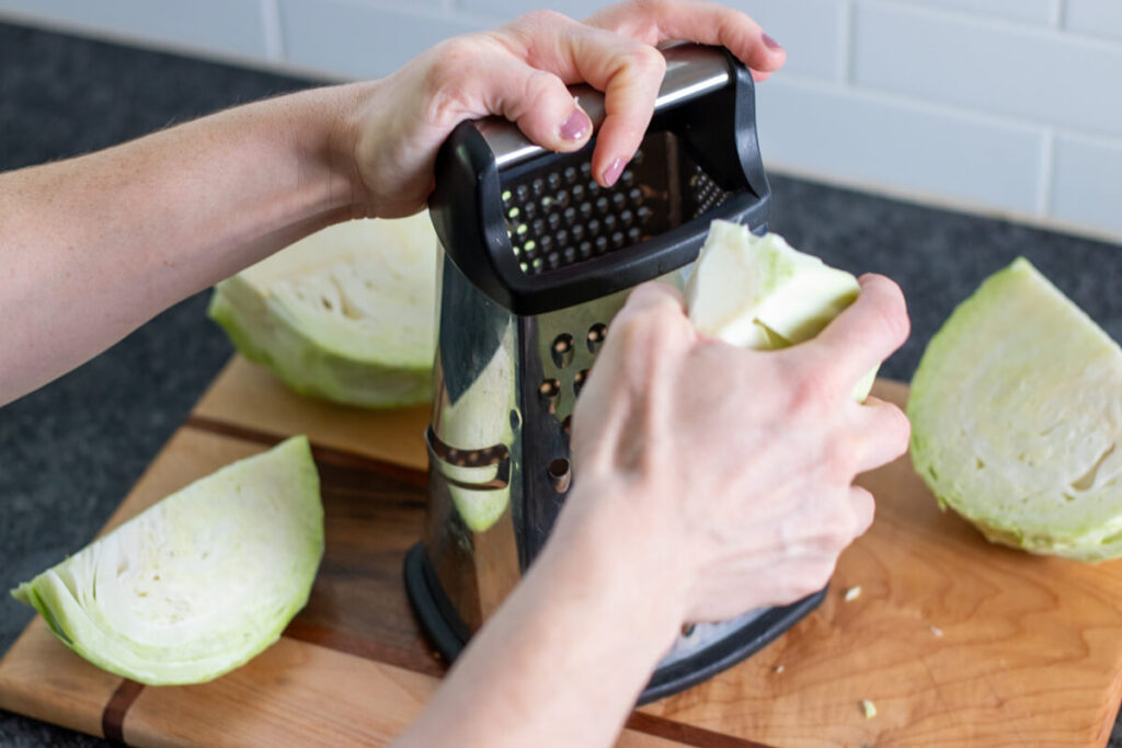 a piece of cabbage being shredded on a grater