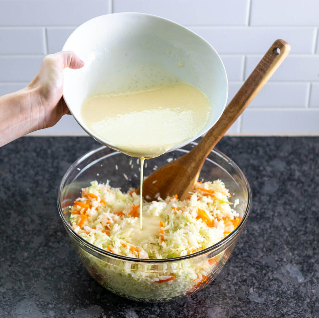 pouring dressing onto cabbage mixture