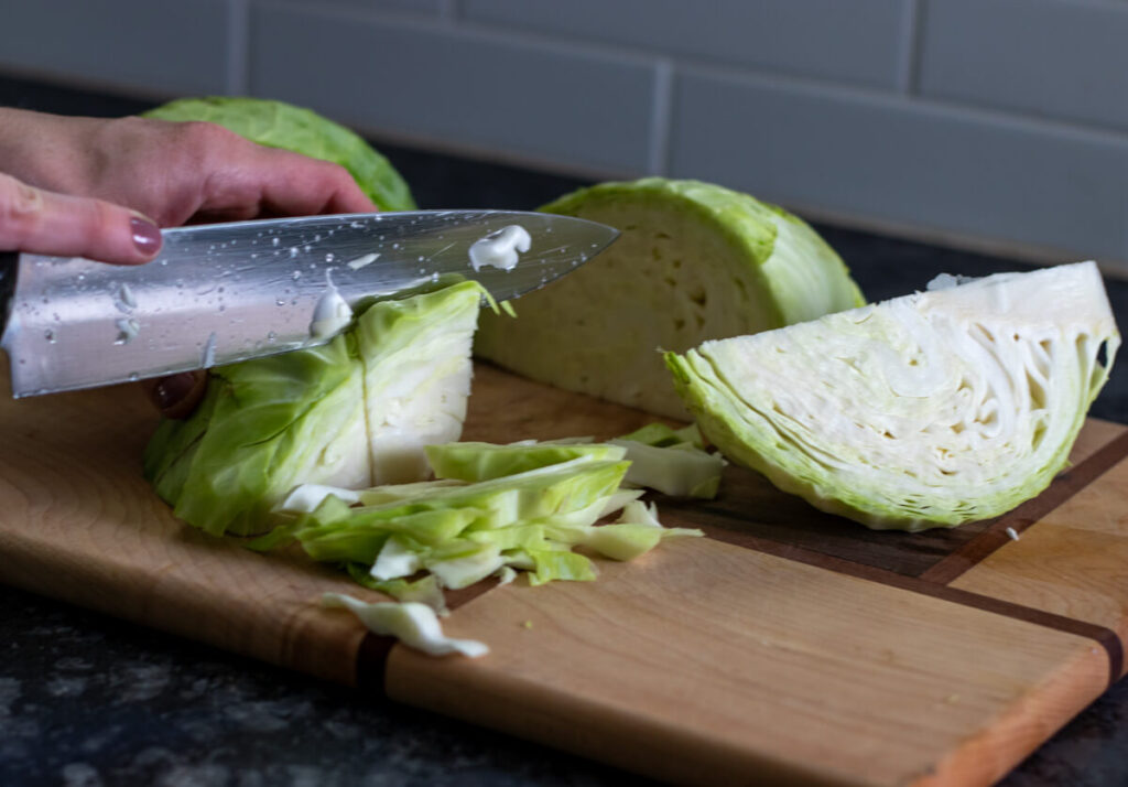 cutting up cabbage on a wood cutting board