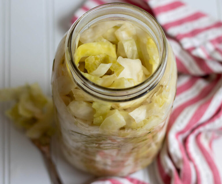 sauerkraut in a glass jar with a tea towel and fork